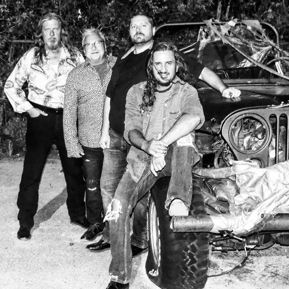 Motorworks Brewing presents MORE is MORE band posing in front of jeep in black and white